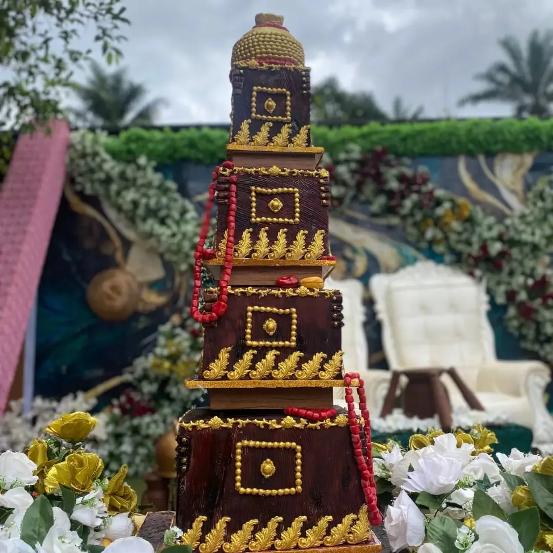 Tall dark brown and gold traditional celebration cake with red bead details